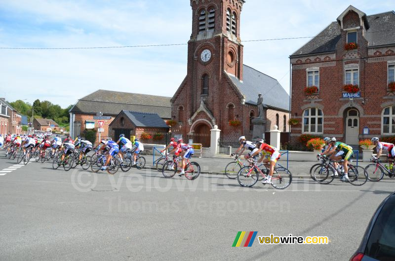 Het peloton komt langs het gemeentehuis en de kerk van Montay