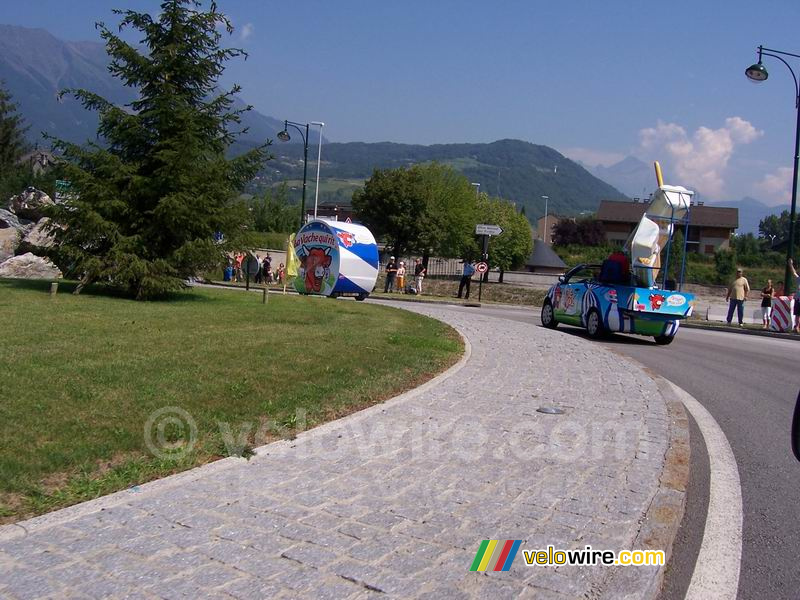 De La Vache Qui Rit verpakking en één van de auto's op een rotonde - [1 dag in de reclamecaravaan van La Vache Qui Rit]